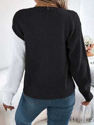 Asymmetrical knit sweater with colorblock black and white sleeves, button detail, 100% acrylic.