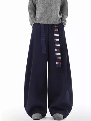 Navy blue ultra-comfort wide-leg sweatpants with a striped belt and grey shoes.