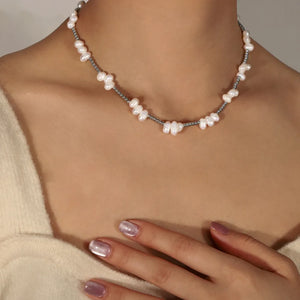 Irregular pearl cluster necklace in silver with small grey beads, styled casually on a woman.