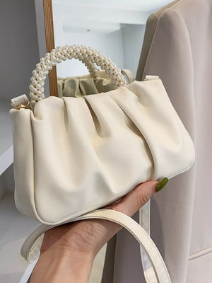 Elegant pearl-handled mini crossbody bag in rice white with ruched detail and gold hardware.