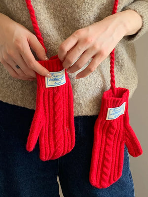 Red cable knit acrylic gloves with braided detail and a connecting strap.