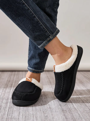 Black suede moccasin slides with cozy shearling lining and a decorative stitch detail.
