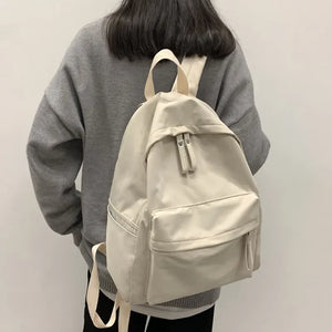 Ivory canvas school backpack with dual pockets and adjustable straps.