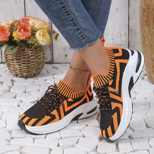 Geometric knit platform sneakers in orange and black with white soles.