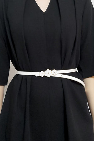 White skinny belt with floral blossom detail cinching a black dress