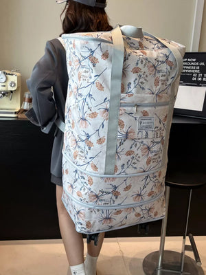 Charming floral rolling travel bag in white with blue and coral floral print, featuring top handles and wheels.