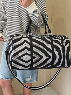 Large black and white zebra print duffle bag with carry handles and detachable strap.