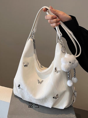 White shoulder bag with butterfly appliques and a cloud charm with pom poms.
