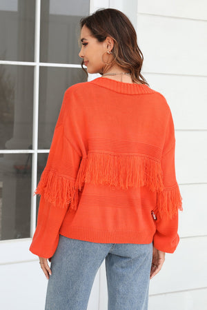Orange acrylic cardigan with fringe detail on sleeves and back, crew neck, long sleeves.