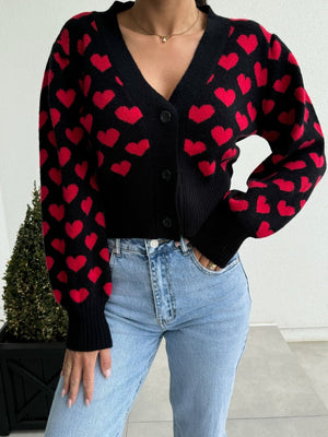 Black knit cardigan with red hearts, puff sleeves, and a V-neck.