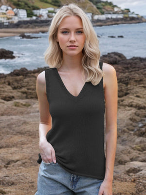 Black knit tank top with deep V-neck and tie straps, styled with denim shorts.