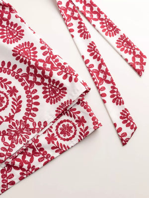Deep red floral print tie-waist romper with white fabric detail.