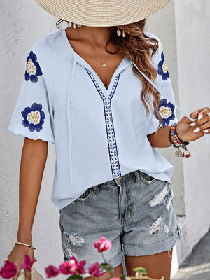 Light blue embroidered yoke sleeve blouse with floral details and tie neckline.