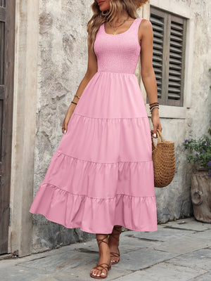 Pink smocked bodice tiered maxi dress with scoop neck and sleeveless design.