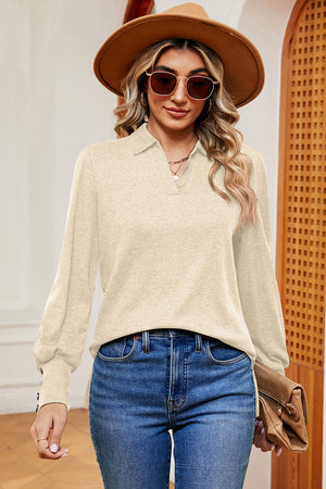 Cream buttoned blouse with V-neck and balloon sleeves, detailed with cuff buttons.