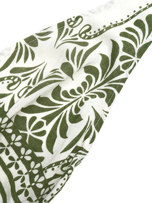 White halter neck jumpsuit with green botanical print and floral border detail.