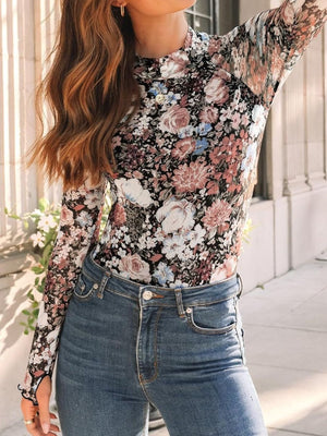 Romantic floral mesh top with mock neck and long sleeves, styled with jeans.
