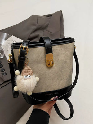 Bucket bag with fuzzy charm, gold hardware, and black trim.