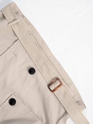 Beige cropped double-breasted trench coat with belt and tortoise buckle detail.
