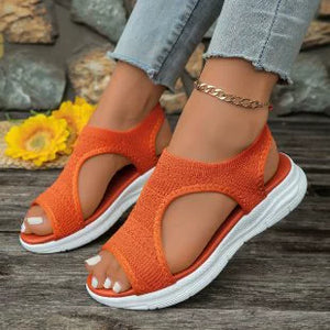 Orange open-toe platform sandals with white soles and a textured knit upper.