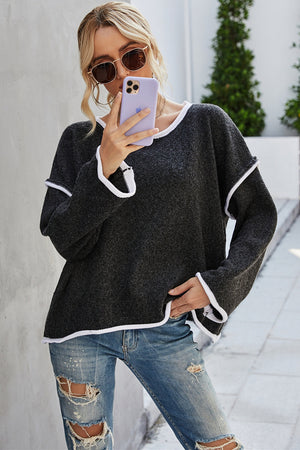 Oversized knit sweater in black with white contrast trim and frayed details.