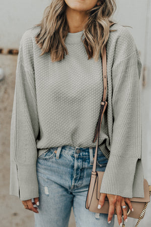 Gray textured knit sweater with crew neck and split sleeves, styled with jeans.
