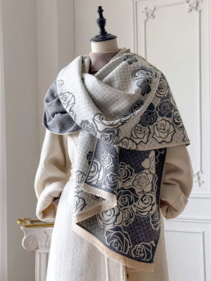 Elegant floral pattern scarf in gray and white with fringe detail.