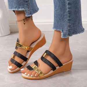 Glistening black and gold dual-strap wedge sandals with comfortable cork sole.