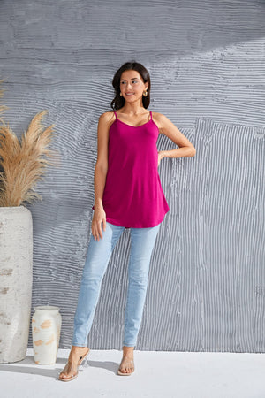 Cerise cami with spaghetti straps and curved hemline, worn with light wash jeans.