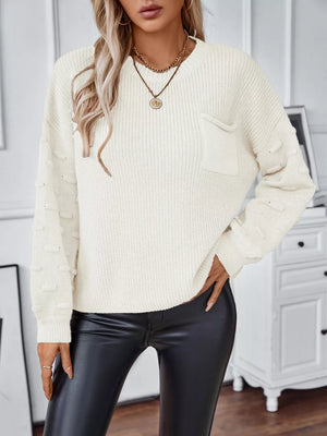Ivory knit sweater with textured sleeves and a chest pocket.