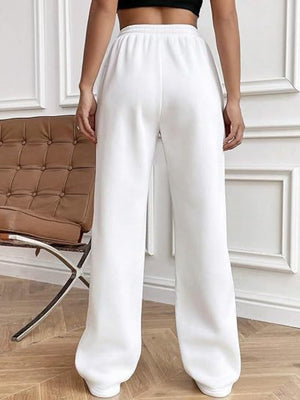 White pleated wide-leg lounge trousers with elastic waistband and cuffed ankles.