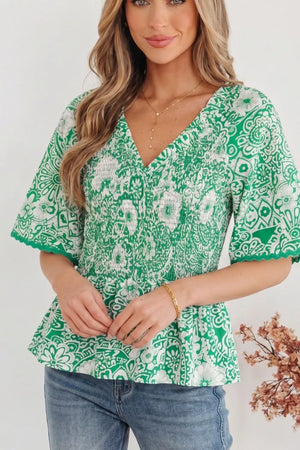 Green floral smocked v-neck polyester overshirt with ruffled sleeves.