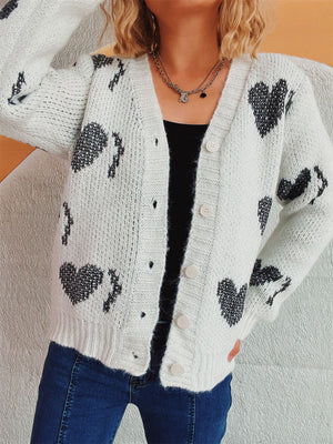 White knit cardigan with black heart motif, button front, V-neck, long sleeves.