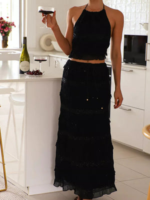 Black halter neck smocked two-piece ensemble with tiered ruffled skirt.