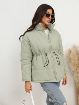 Light green textured puffer jacket with drawstring waist and stand-up collar.