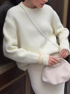 Cozy knit top in cream with relaxed fit and crew neck, styled with a pearl bag.