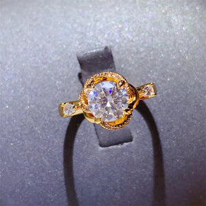 Gold halo ring with moissanite center stone and floral design.