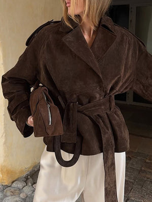 Brown suede trench coat with lapel collar and tie waist, cropped length.