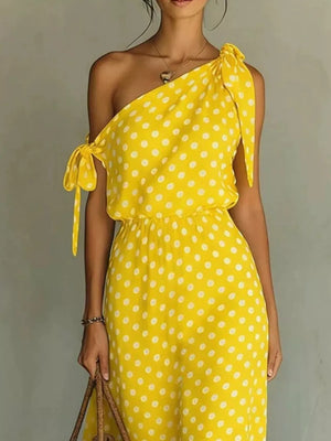 Yellow polka dot one-shoulder maxi dress with cinched waist and tie details.