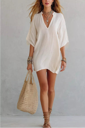 Relaxed white linen-blend mini dress with V-neck and half sleeves, styled with layered necklaces.