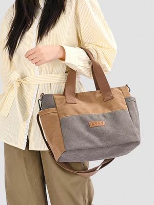 Multi-pocket canvas travel bag in dark gray and taupe with adjustable strap.