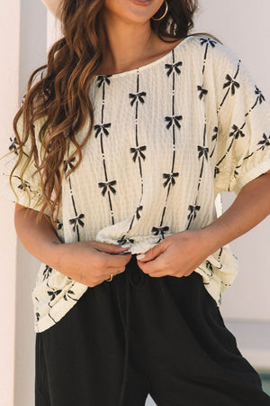 Beige gauze blouse with black bow print and gathered sleeves.