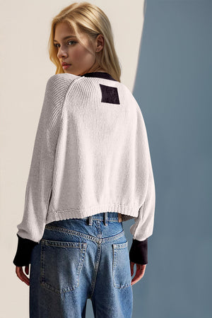 White raglan sleeve cardigan with contrast trim and black square detail on back.