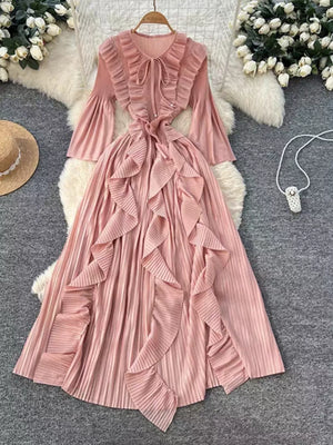 Pink midi dress with cascading ruffles, tie neck, and bell sleeves.