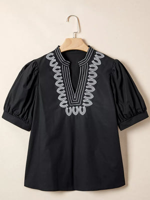 Black maternity overshirt with white embroidered neckline and puff sleeves.