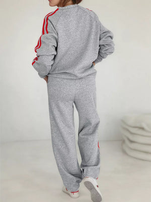 Grey loungewear set with red stripes on sleeves and pants. Crewneck sweatshirt and wide-leg pants.