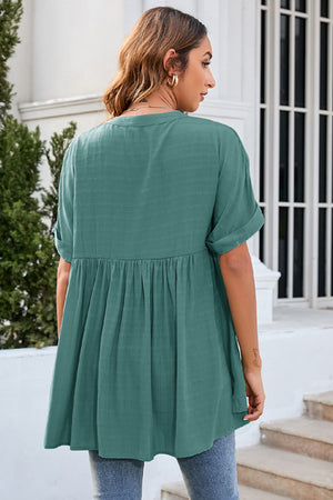 Dark green gathered back yoke blouse with rolled sleeves and a flowy hem.