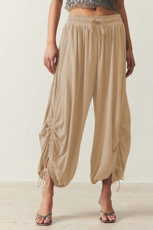 Tan gathered ankle-tie balloon trousers with drawstring waist and ruched side detail.