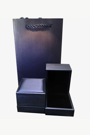 Dark blue gift bag and two open jewelry boxes with black velvet lining.