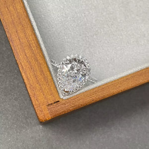 Elegant moissanite teardrop ring in sterling silver with halo accent stones.